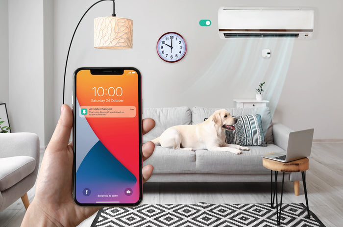 PROMPT: Hand holding iPhone showing Sensibo app with AC controls, temperature at 24C, multiple rooms listed, blurred modern living room in background, warm tones, lifestyle product photography