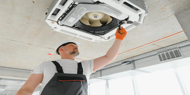 Technician servicing a ceiling cassette unit