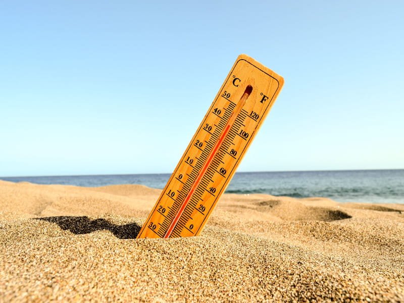 Thermometer in beach sand at peak daytime heat